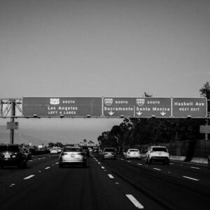 A black and white photo of a busy Los Angeles highway with visible signboards.