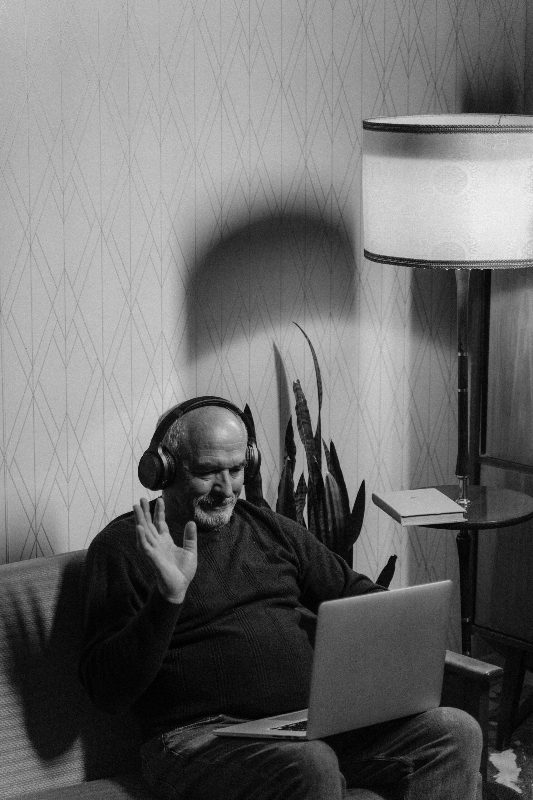 Elderly man wearing headphones engaging in an online video call from home.